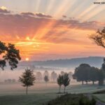 Imagem de um nascer do sol sereno em uma paisagem tranquila, simbolizando uma quinta-feira abençoada.