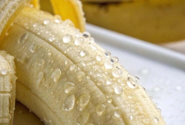 Banana madura com gotas de água na casca, destacando sua textura e cor vibrante.