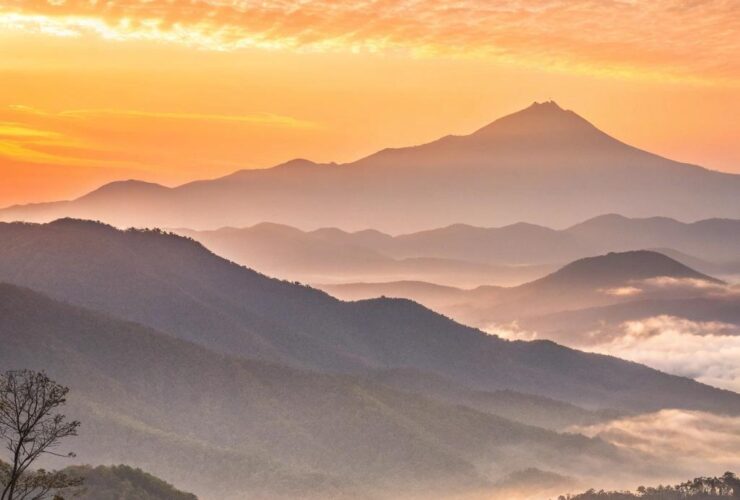 Nascer do sol tranquilo sobre uma paisagem montanhosa, simbolizando um novo começo inspirador.