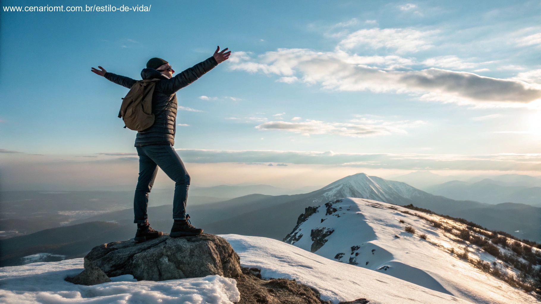 Uma pessoa em pé no pico de uma montanha com os braços abertos, abraçando a luz do sol e uma vista deslumbrante, simbolizando motivação para o sábado.