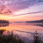 Um nascer do sol sereno sobre um lago calmo com cores pastéis suaves, simbolizando uma manhã de sexta-feira pacífica e inspiradora em 17 de janeiro de 2025.