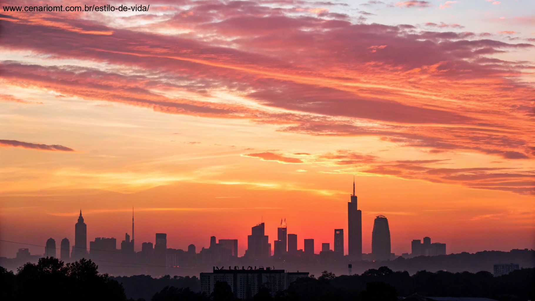Nascer do sol vibrante sobre o horizonte de uma cidade, com tons quentes de laranja e rosa se espalhando pelo céu, representando a energia e positividade de uma manhã de quinta-feira, 16 de janeiro de 2025.