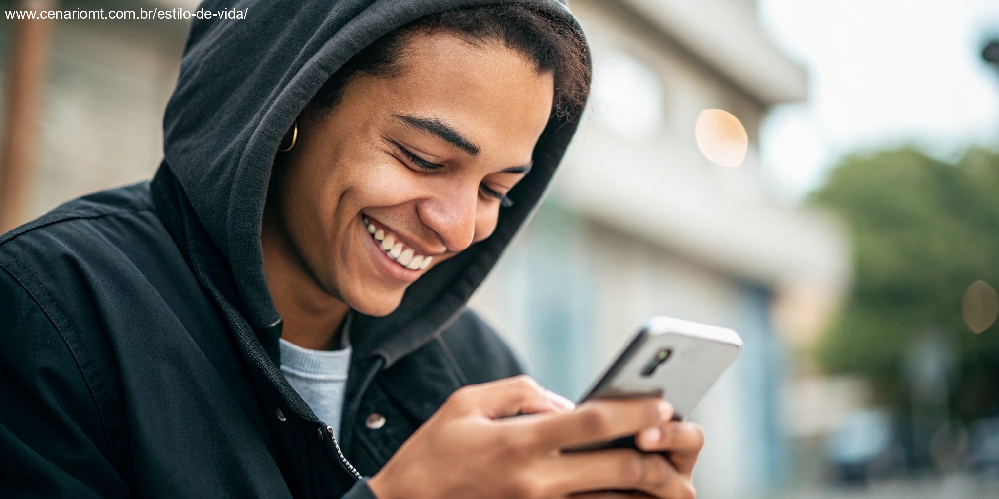 Pessoa sorrindo ao ler uma mensagem de bom dia no celular