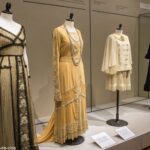 Uma coleção de roupas vintages de diferentes épocas exibidas em manequins em um museu de moda.