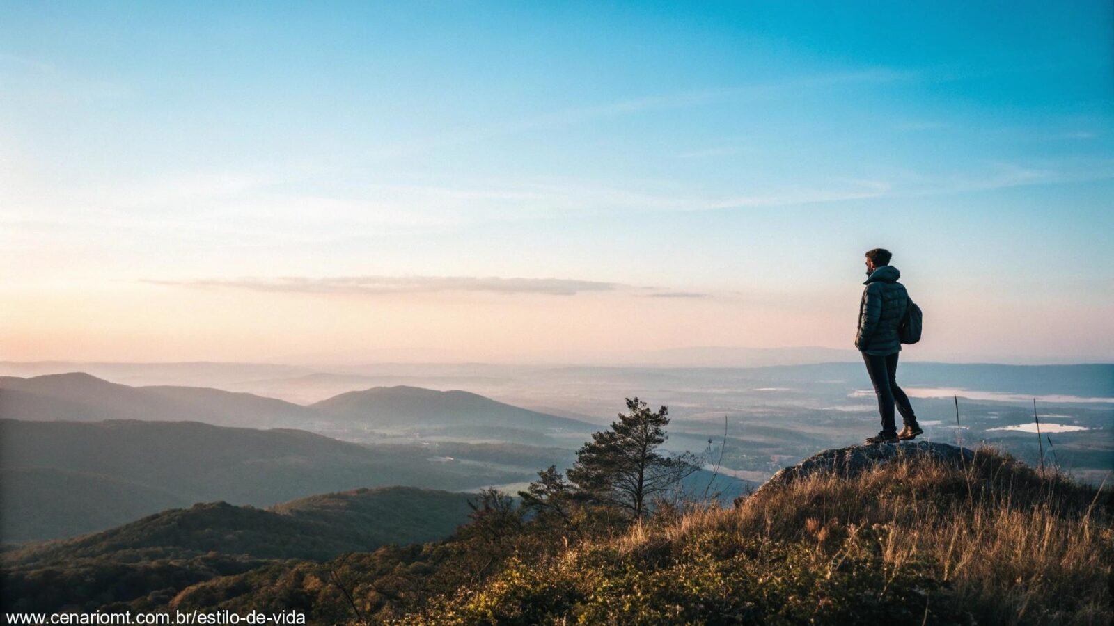 Uma paisagem serena com uma pessoa de pé no topo de uma montanha, contemplando um vasto horizonte.