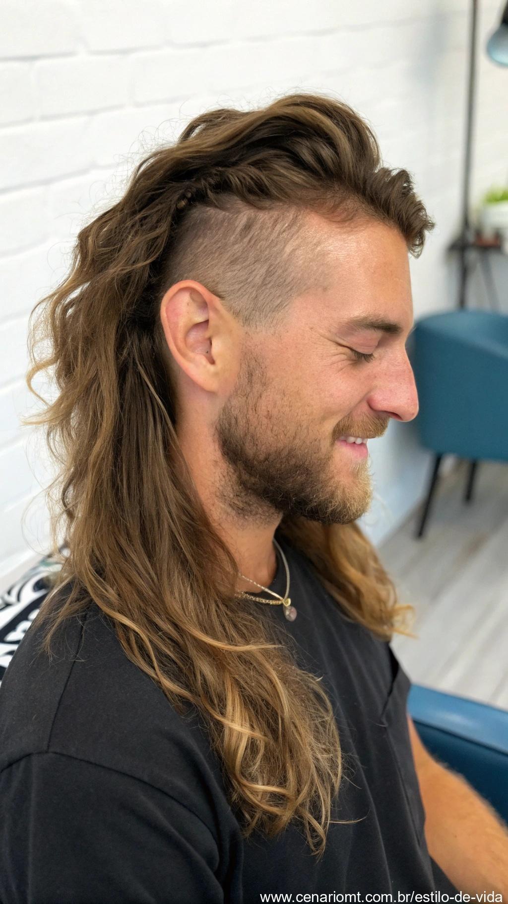 Homem com cabelo longo, com estilo natural e personalizado, em ambiente descontraído.