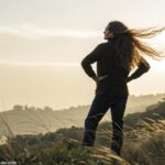 Pessoa com cabelo longo, em um ambiente natural, transmitindo confiança e estilo.