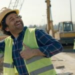 Pedreiro sorridente em um canteiro de obras fazendo uma cantada exagerada