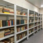 Estante de livros organizada em um ambiente seco e fresco, com livros armazenados de forma correta para evitar o crescimento de fungos.
