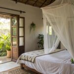Quarto tranquilo com mosquiteiro sobre a cama e iluminação natural.