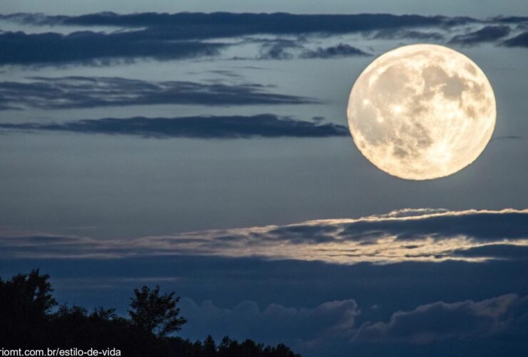 Uma vista clara de uma lua cheia brilhante no céu noturno com nuvens sutis ao redor.