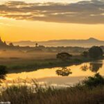 Amanhecer tranquilo sobre uma paisagem serena, com luz dourada aquecendo o céu, transmitindo calma e reflexão espiritual.
