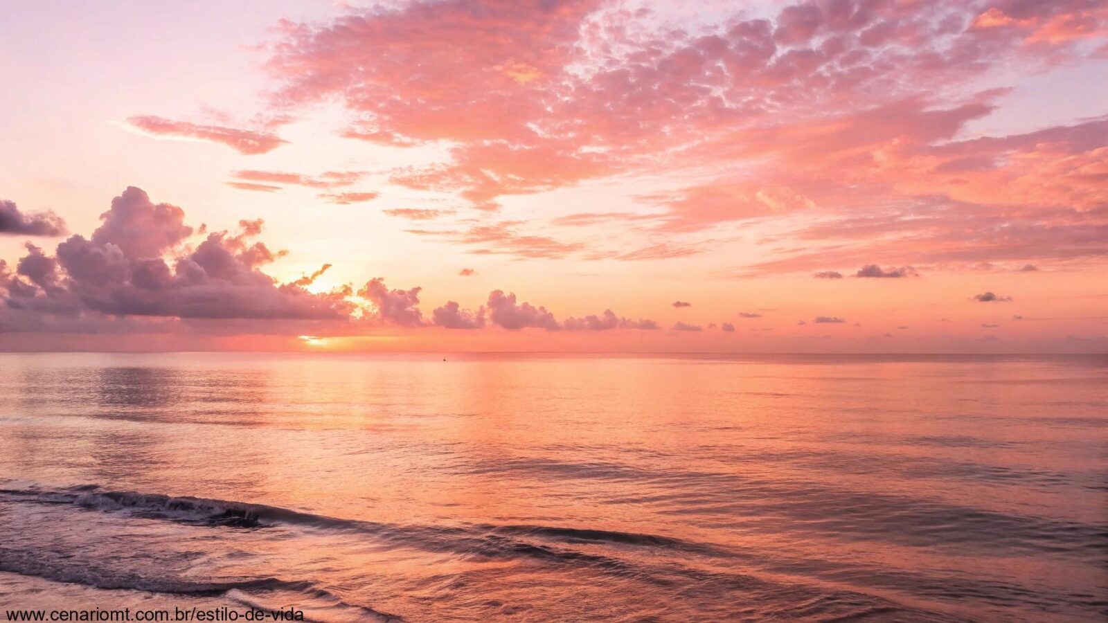 Amanhecer tranquilo sobre o mar, com tons suaves de rosa e laranja, transmitindo serenidade e carinho.