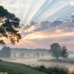 Cenário pacífico pela manhã com o sol nascendo sobre uma paisagem tranquila, simbolizando esperança e serenidade para grupos religiosos do WhatsApp.