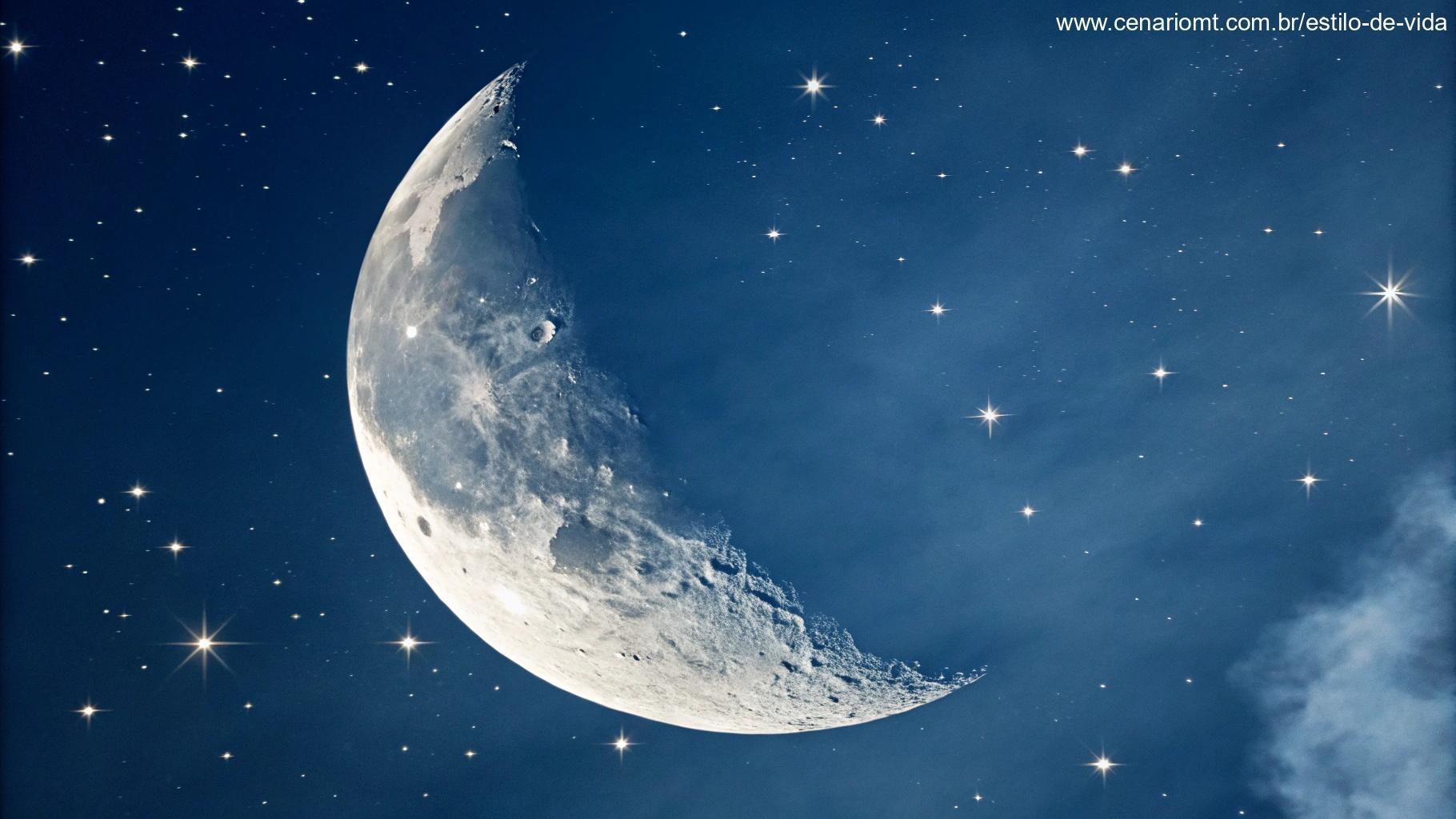 Uma vista de perto da lua crescente iluminada no céu azul profundo com estrelas delicadas ao redor.