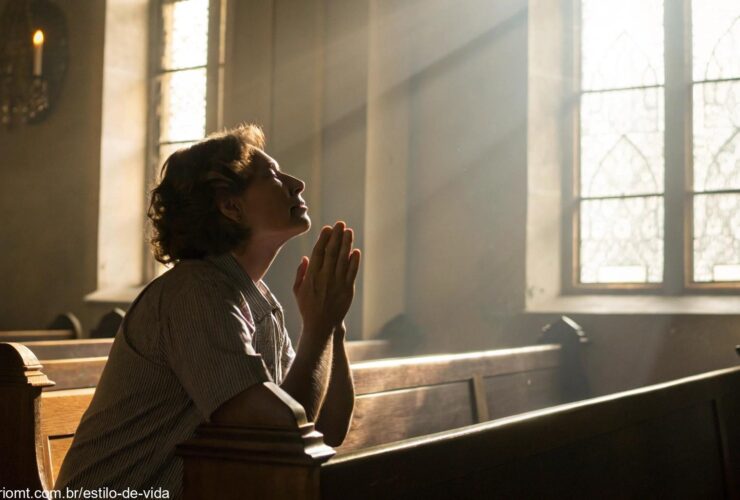 Pessoa em oração sob a luz suave do amanhecer em uma igreja.