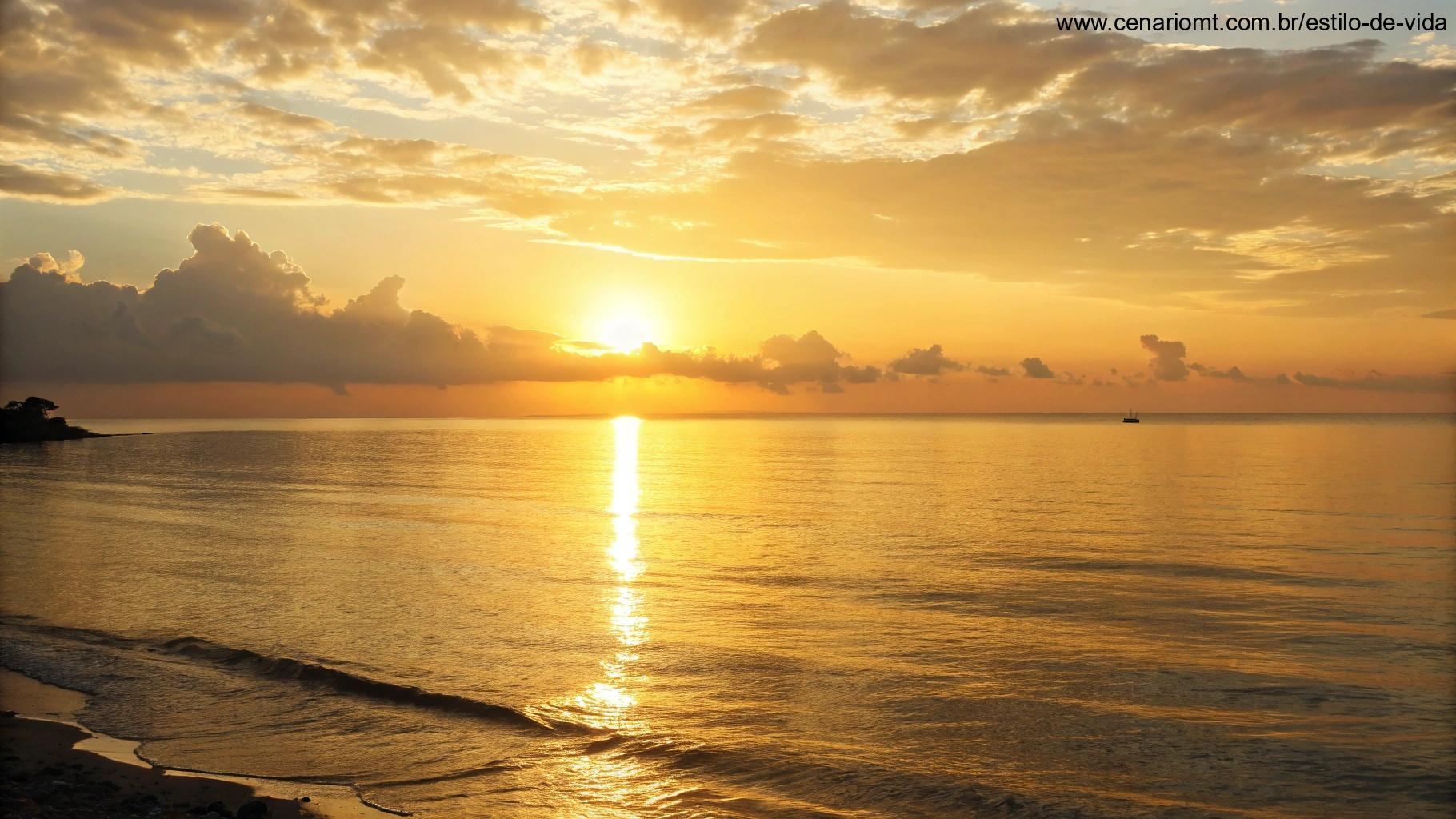 Amanhecer calmo sobre o horizonte, com luz dourada refletindo no mar tranquilo.