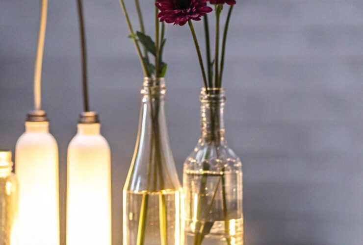 Diversos frascos de vidro reutilizados de forma criativa, incluindo arranjos florais, armazenamento e iluminação, exibindo um design moderno e artístico.