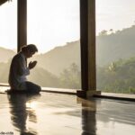Cena serena e pacífica de uma pessoa orando, com luz natural suave e uma atmosfera calma, refletindo um momento de reflexão e conexão espiritual.