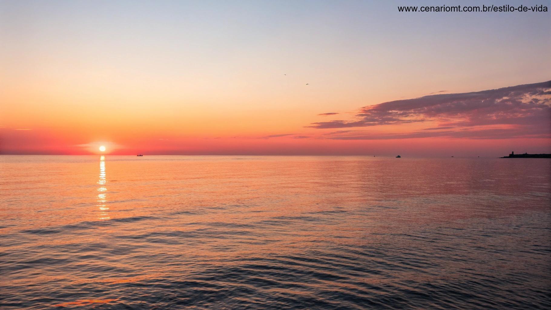 Pôr do sol calmo e sereno sobre o oceano, com tons quentes de laranja e rosa refletindo na água.