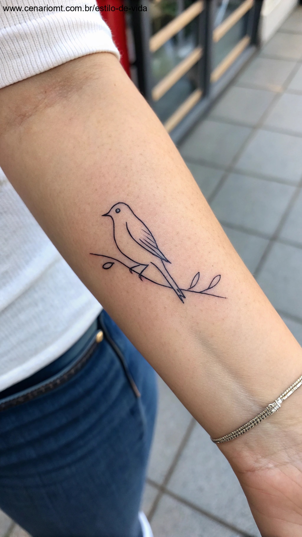 Tatuagem minimalista delicada de um pássaro no pulso.