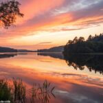 Paisagem tranquila com um pôr do sol sobre um lago calmo, simbolizando reflexão e paz espiritual.