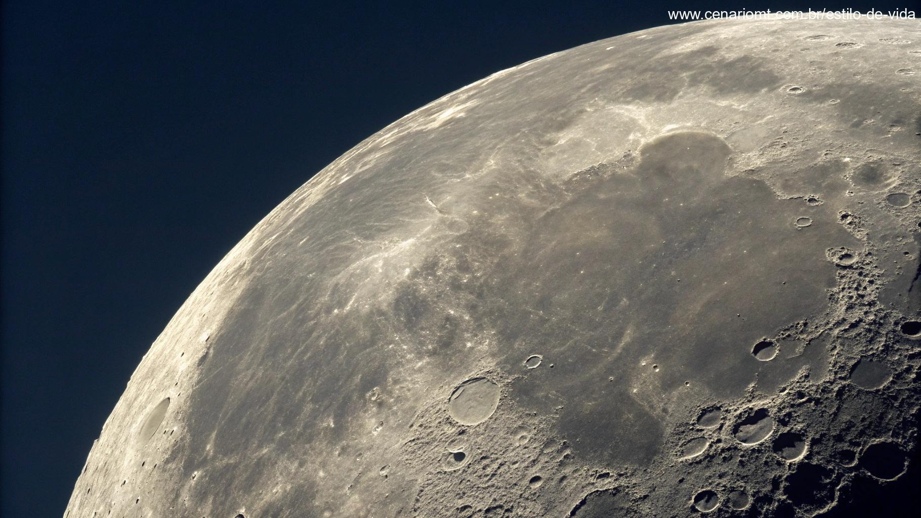 Vista detalhada da superfície da lua durante a fase gibosa minguante, destacando crateras, montanhas e mares lunares, com um céu escuro ao fundo
