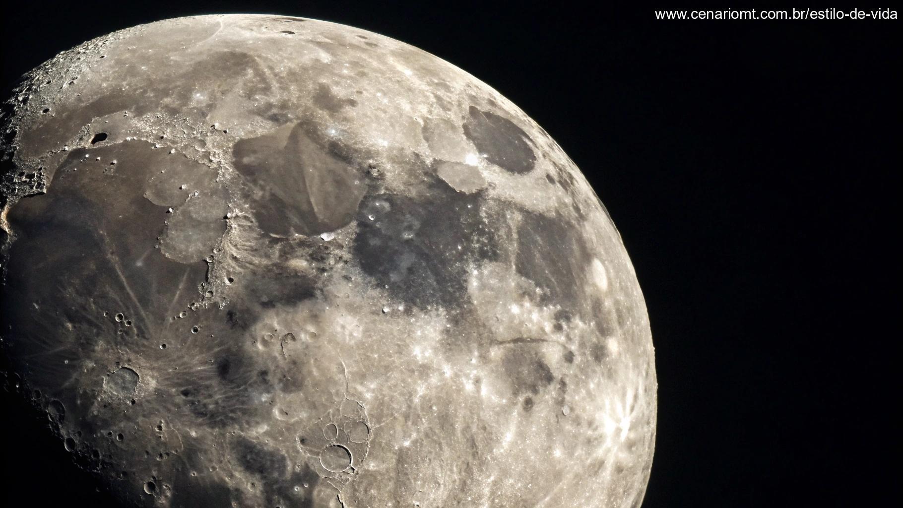 Vista detalhada de uma lua gibosa minguante, mostrando sua superfície texturizada com crateras e sombras, em um fundo preto