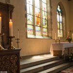 Altar de igreja sereno e pacífico, com velas acesas, refletindo uma atmosfera calma de um serviço de terça-feira de manhã, com luz natural passando pelas janelas de vitrais.