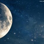 Visão detalhada da lua crescente em um céu claro à noite, com luz suave refletindo na superfície da lua. O fundo mostra um céu escuro cheio de estrelas.
