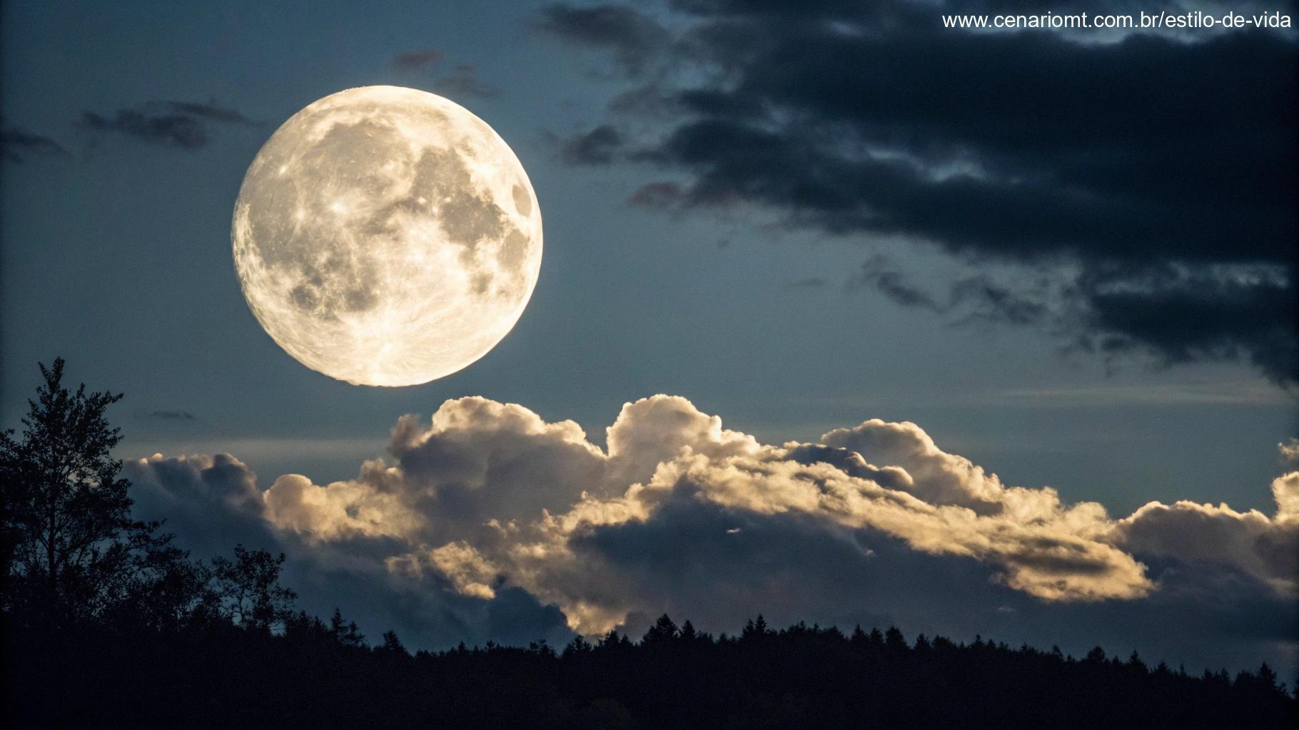 Fase da Lua Gibosa Crescente, com a lua brilhando intensamente no céu escuro, rodeada por algumas nuvens.