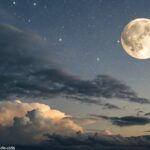Céu noturno sereno com uma lua gibosa minguante, parcialmente iluminada, cercada por estrelas fracas e nuvens suaves