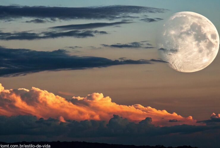 Vista deslumbrante da Lua Gibosa Crescente no céu noturno, com nuvens suaves passando e um toque do brilho laranja do pôr do sol refletindo no horizonte.