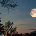 Imagem da Lua na fase Gibosa Minguante em 20 de março de 2025, com crateras visíveis e céu estrelado ao fundo.