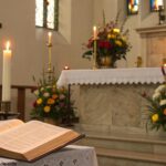 Altar de igreja com velas e flores, simbolizando o Dia Internacional da Mulher em 08 de março de 2025.