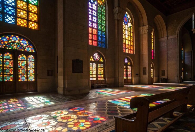 Cena tranquila de um interior de igreja com luz suave vindo através das janelas de vitrais, destacando a reflexão da liturgia do dia.