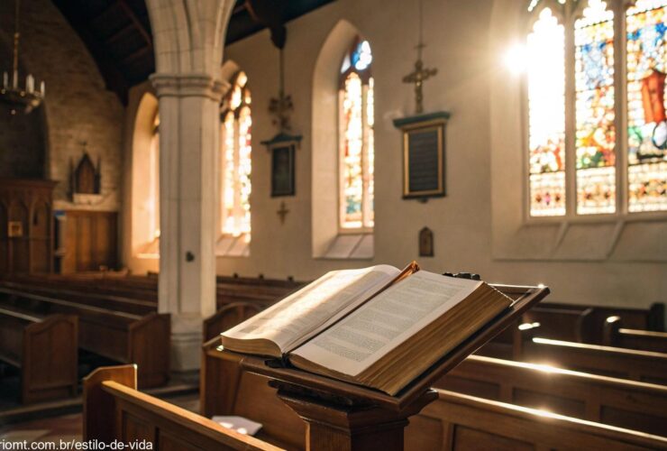 Interior sereno de uma igreja com luz suave através dos vitrais e uma Bíblia aberta em um púlpito de madeira.