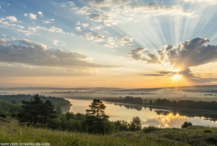 Imagem de uma paisagem tranquila ao amanhecer, com raios suaves de luz e nuvens leves, transmitindo paz e serenidade, ideal para uma mensagem de Bom Dia Abençoado no domingo.