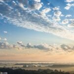 Imagem de uma manhã serena com céu claro e nuvens suaves, simbolizando uma mensagem de esperança e fé para uma quinta-feira abençoada.