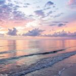 Amanhecer pacífico sobre um oceano calmo, com cores suaves no céu, simbolizando esperança e serenidade para uma manhã abençoada de sexta-feira.