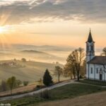 Um amanhecer tranquilo sobre uma igreja, com raios de luz suave iluminando uma paisagem rural, simbolizando esperança e um novo começo para um grupo religioso no domingo pela manhã.