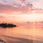 Imagem de um nascer do sol sereno sobre o mar calmo, simbolizando o começo de uma manhã positiva e inspiradora de terça-feira.
