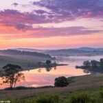 Imagem de um amanhecer tranquilo sobre uma paisagem serena, com cores suaves e uma atmosfera calma, evocando sentimentos de inspiração e paz.