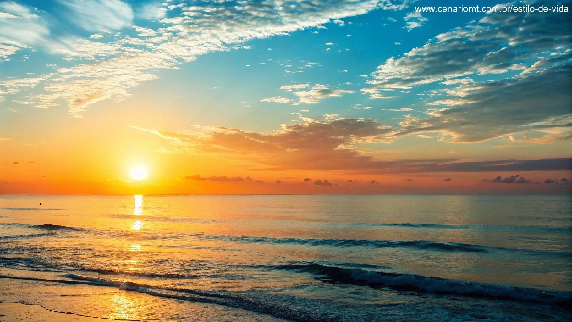 Imagem do nascer do sol sobre um oceano calmo, com o céu transicionando de laranja para azul, transmitindo esperança e positividade.