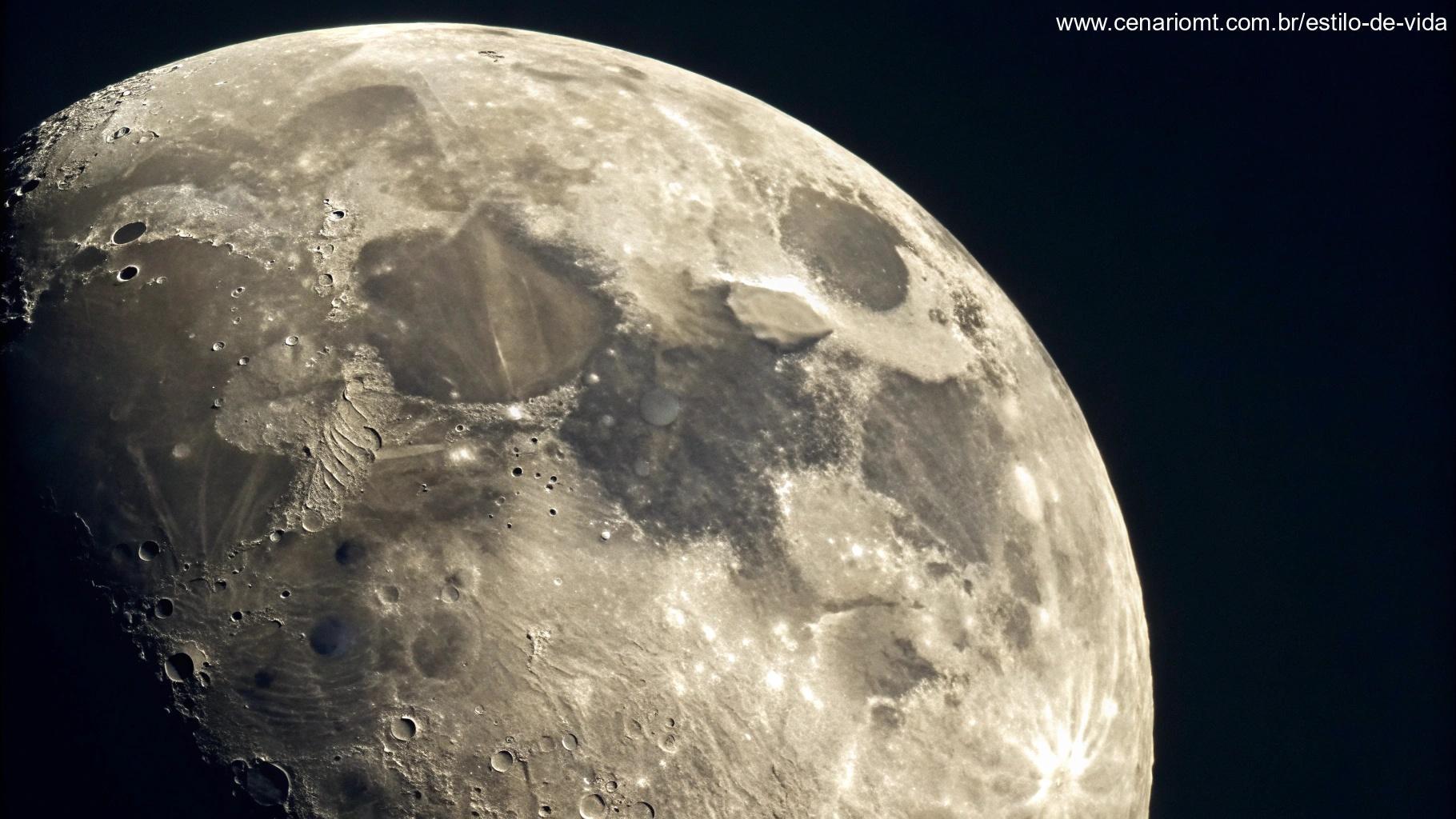 Close-up detalhado de uma lua gibosa minguante, mostrando sua superfície texturizada com crateras e sombras, contra um fundo escuro e sem estrelas