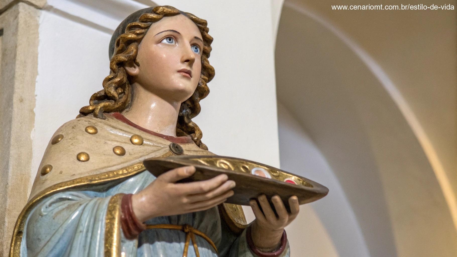 Estátua detalhada de Santa Luzia segurando um prato com olhos, simbolizando proteção sobre a visão.