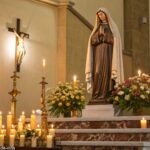 Imagem de um altar de igreja com uma estátua de Santa Rita de Cássia, rodeada por velas e flores.