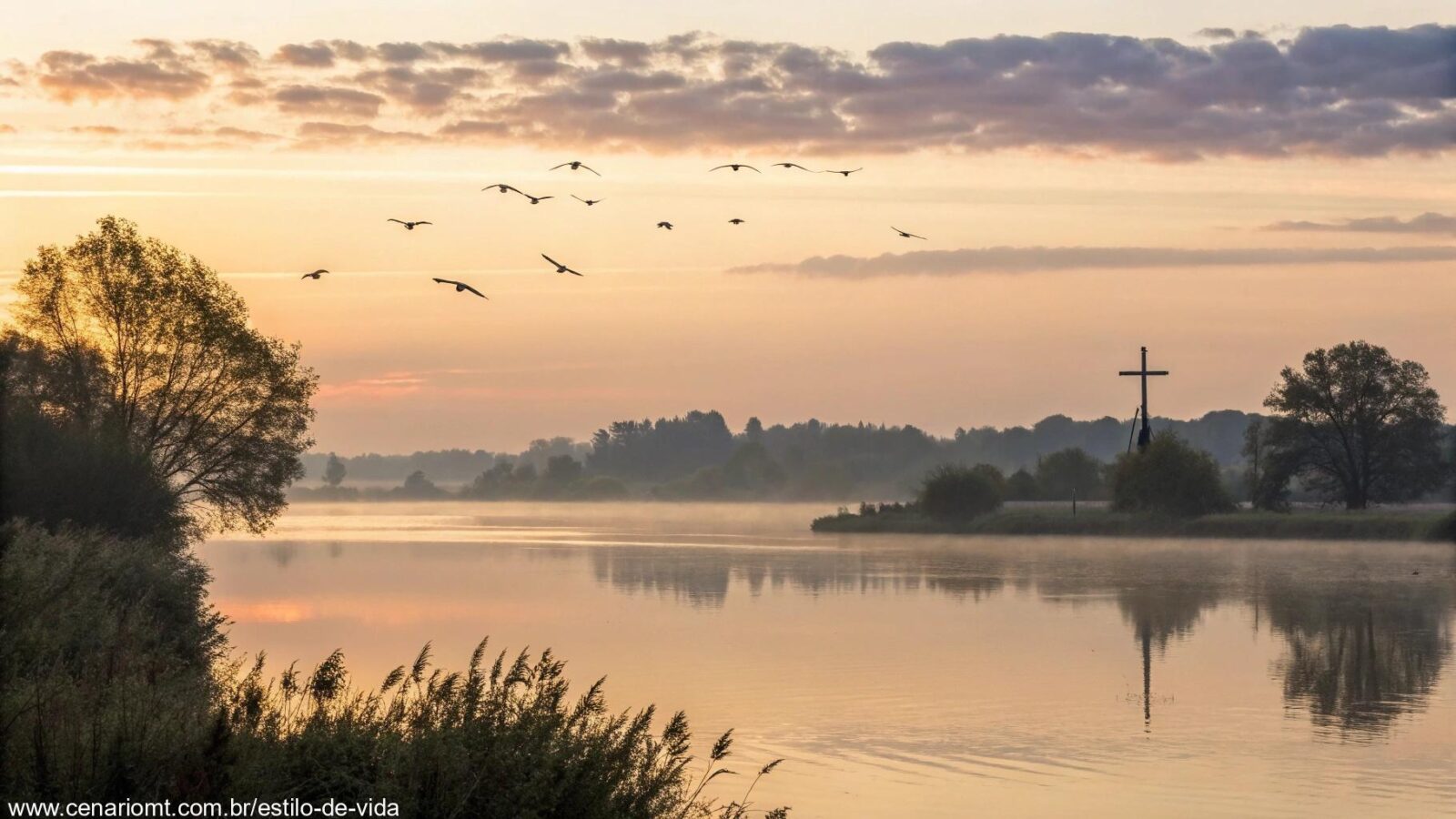 Paisagem tranquila com um suave nascer do sol sobre um lago calmo, aves voando no céu e uma pequena silhueta de cruz ao longe.