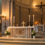 Cena pacífica de um altar de igreja com velas acesas, celebrando o Dia Internacional da Mulher com foco na fé e devoção.