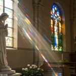 Imagem serena de uma estátua de santo em um ambiente tranquilo de igreja, com luz filtrando pelas janelas de vitrais, criando uma atmosfera reflexiva.